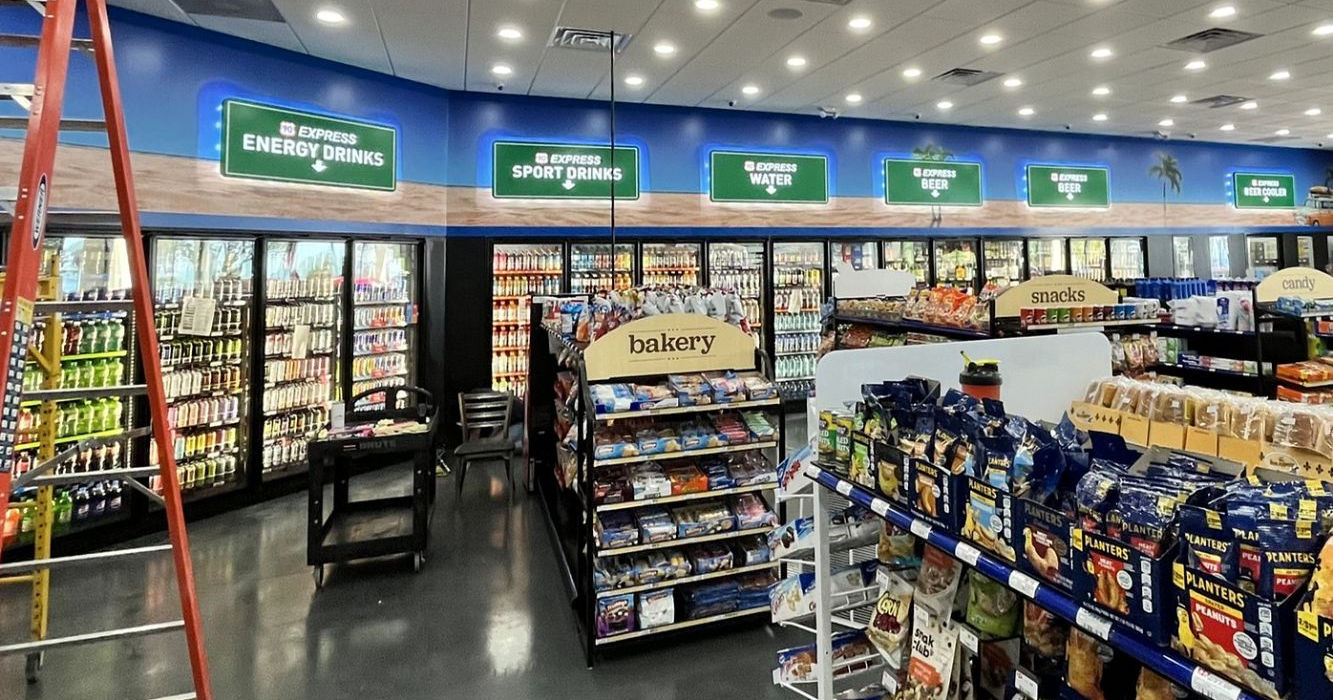 Graphic vinyl wall wrap installed above gas station beverage coolers with drink types designed & installed by Mello Signs.