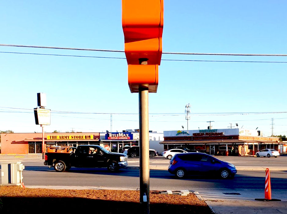 Side view of an orange and white pole pylon sign installed next to a business driveway in Dallas Texas by Mello Signs.