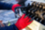 Closeup of an installers hands using the crane truck controls to control the movement of a sign structure being installed.