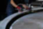 Closeup of an employee sanding/polishing a custom metal fabrication sign component inside the Mello Signs manufacturing plant