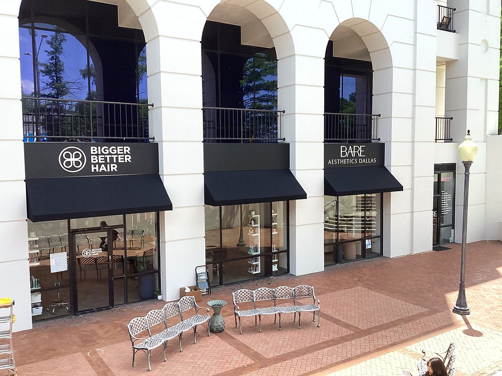 White concrete block building with black canopy/overhang style storefronts, each with white business signs on the black.