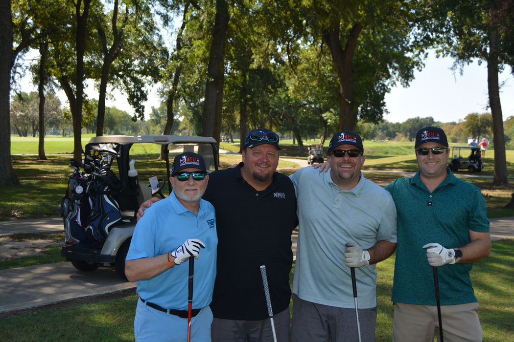 Group of 4 people on a golf course at the Mello Signs' Charity Golf Classic, benefitting children's cancer research.