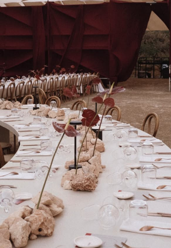 Mesa de banquete curva decorada con piedras y flores