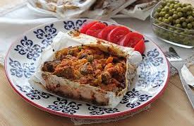 Geleneksel kağıt kebabı sunumu; yağlı kağıtta fırınlanmış kuşbaşı et ve garnitürlü sebzelerle hazırlanan meşhur ana yemek