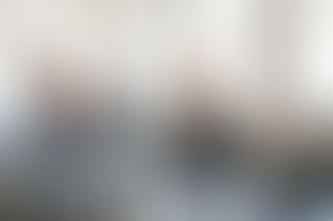 Aydınlık bir stüdyoda grup halinde yoga dersi; mat üzerinde kolları yukarı kaldırarak yapılan savaşçı pozu ve esneme hareketi