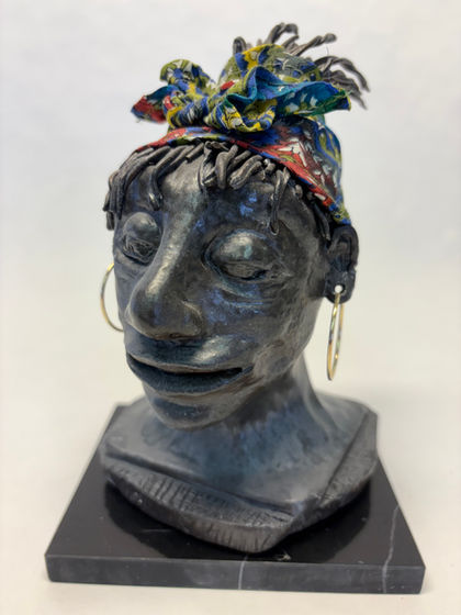 African lady head. Color of clay fired to oxide black.  Head wrap is multicolored. Hoop earrings