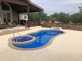 Freeform backyard pool with attached spa beside a covered patio