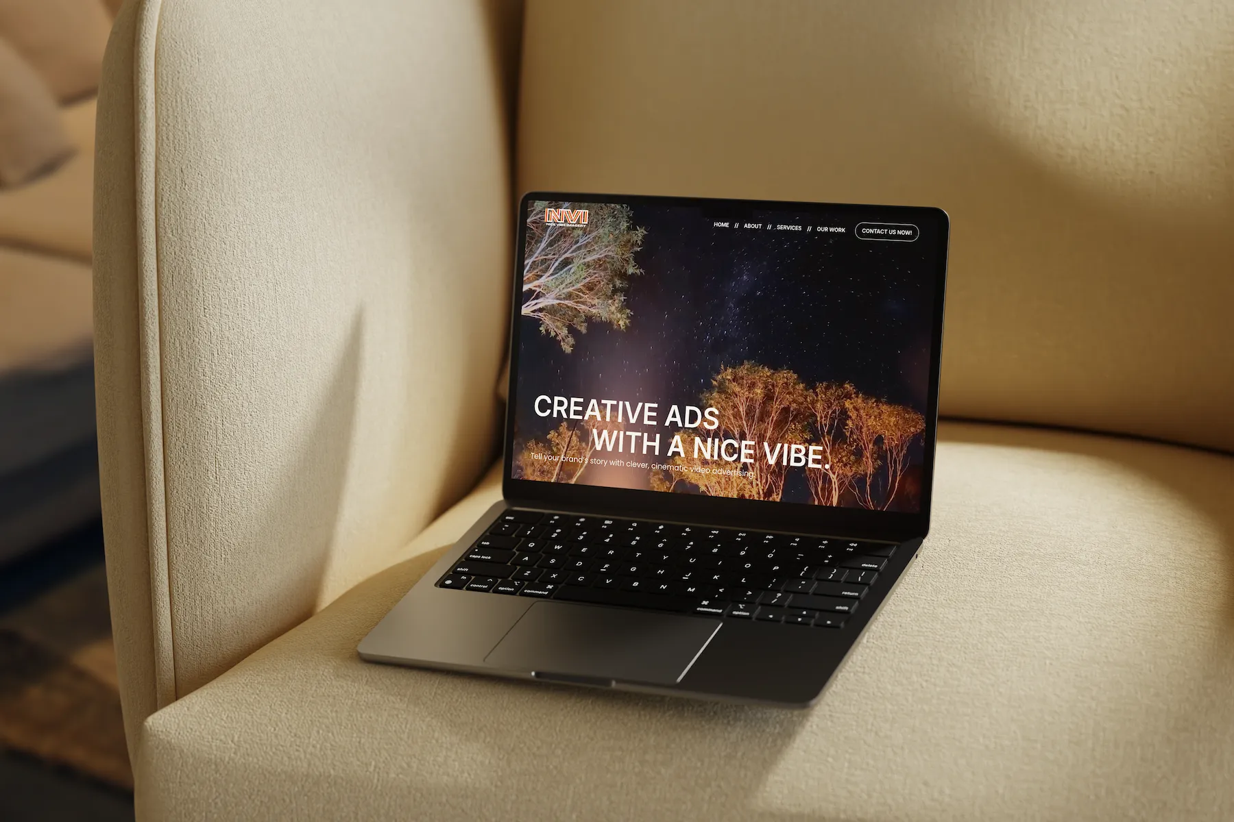Mockup of the Nice Vibe Imagery homepage displayed on a laptop, placed on a beige chair in natural light.