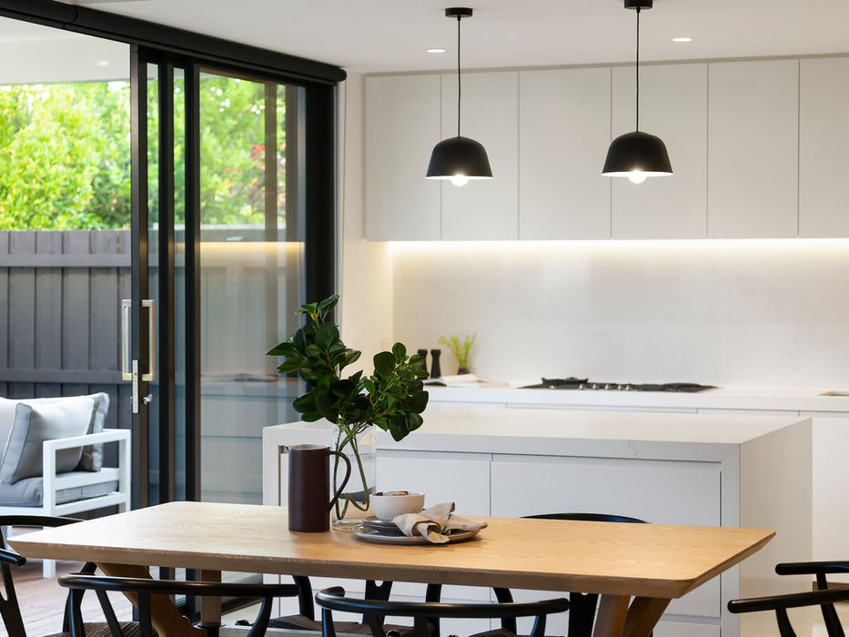 Modern kitchen design with wooden dining table and black pendant lights.