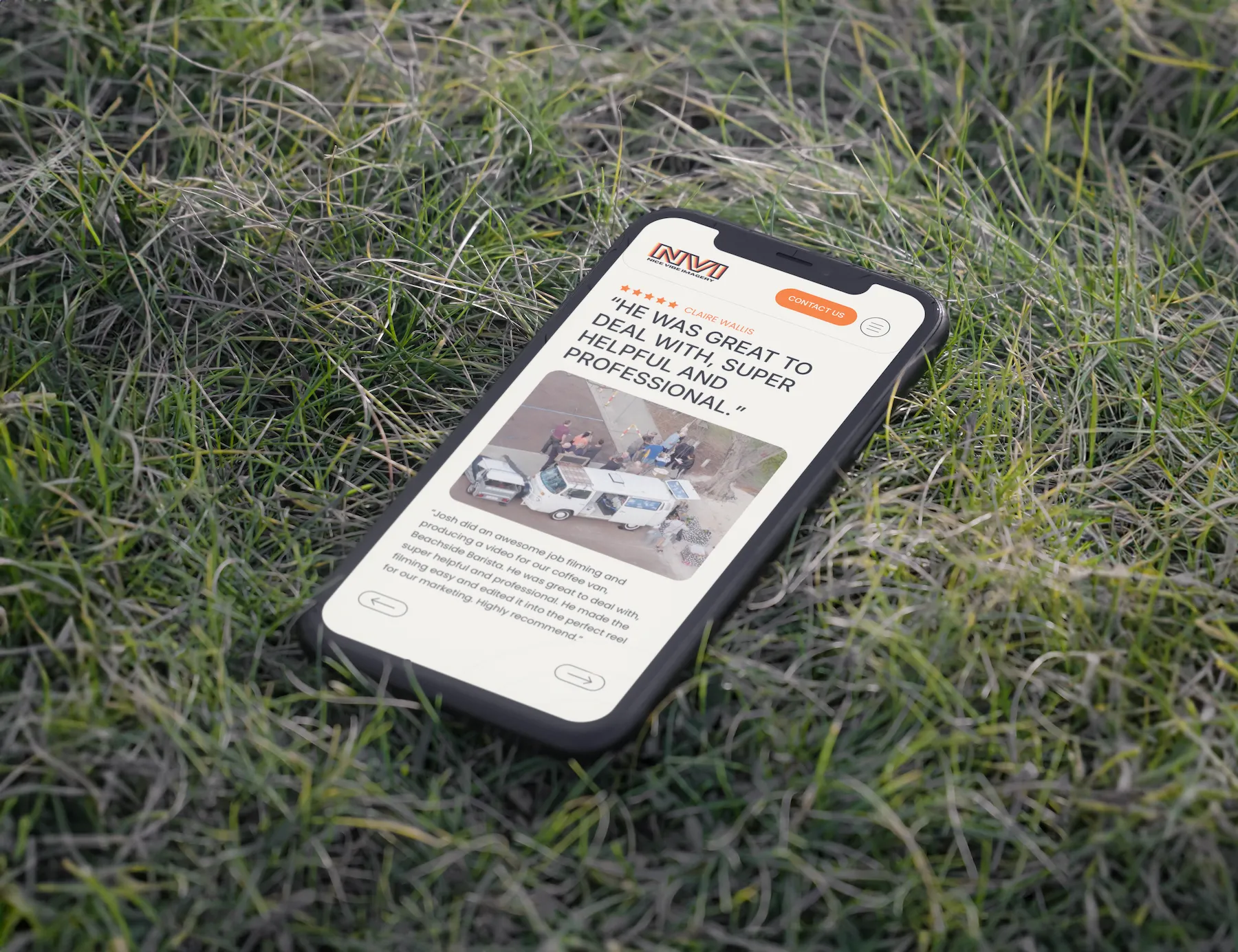 Mobile version of the Nice Vibe Imagery website displayed on a smartphone placed on green grass, showcasing mobile responsiveness.