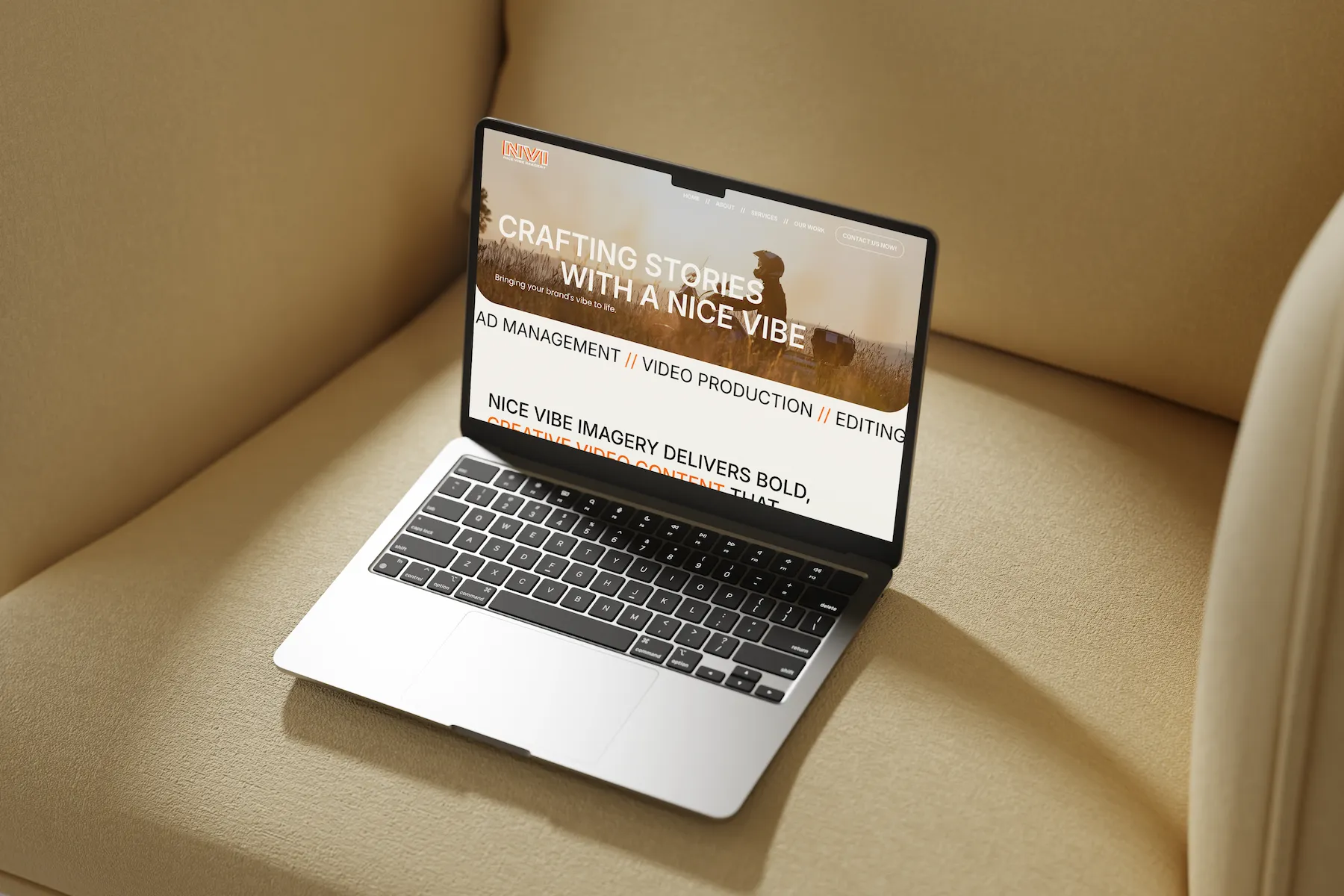 Laptop mockup of the Nice Vibe Imagery homepage resting on a white platform, photographed from an angle.
