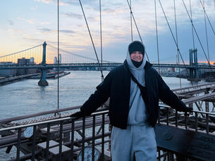 Man standing smiling for a photo on the Brooklyn Bridge