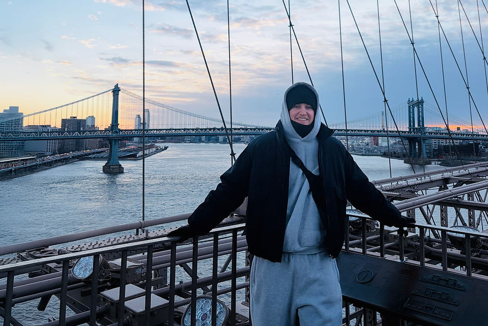 Man standing smiling for a photo on the Brooklyn Bridge