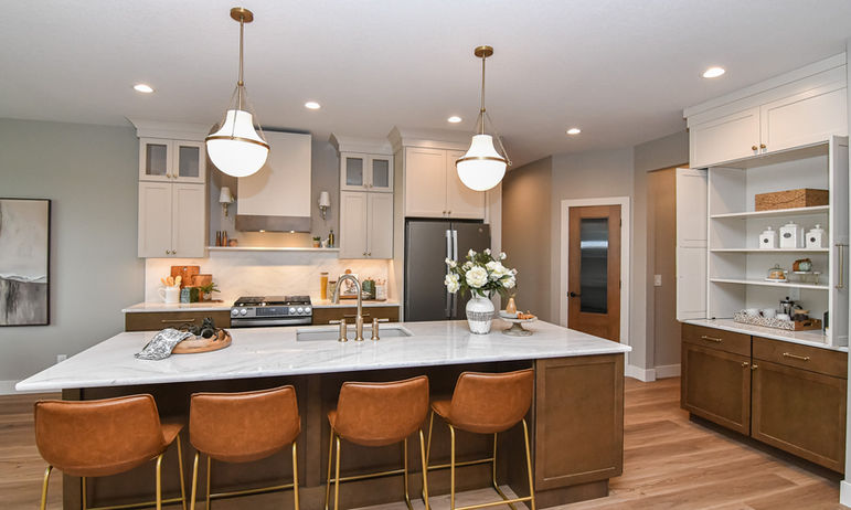 Professionally styled kitchen in a Cedar Falls Parade Home with warm wood cabinetry and island seating.