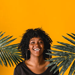 laughing-young-black-woman-with-palm-leaves-colored-background.jpg