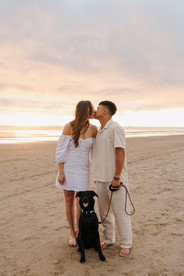 Couple with dog kissing with sunset at Cannon Beach for engagement photography