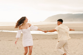 Couple spinning around at Cannon Beach for engagement photography