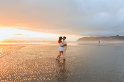 Couple hugging and kissing in the water and sunset at Cannon Beach for engagement photography