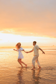 Couple holding hands running in the water and sunset at Cannon Beach for engagement photography