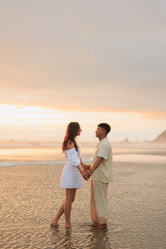 Couple holding hands in the water and sunset at Cannon Beach for engagement photography