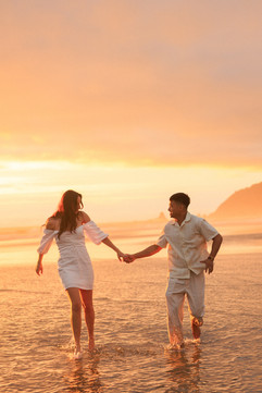 Couple holding hands running in the water and sunset at Cannon Beach for engagement photography