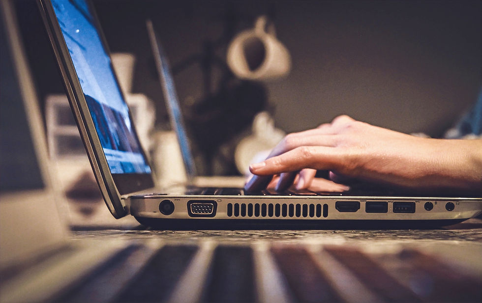 hands visible typing on laptop with coffee mug in background