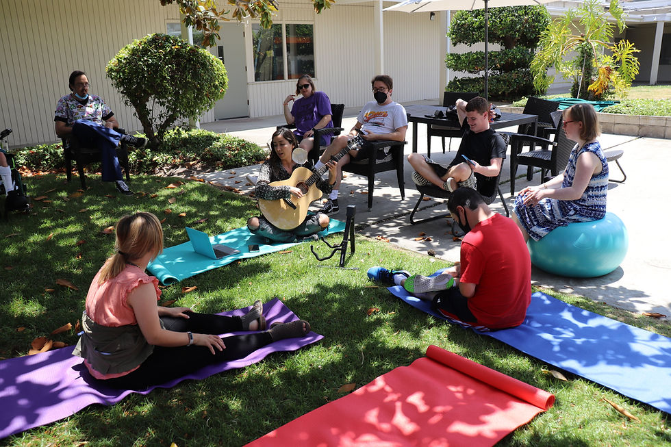 Staff and students at Sand Diego Able ARTS Work sitting outside on yoga mats and chairs. Left to Right: Claire Feth, Danielle Miyazaki (Music Therapist), Stephanie Monis, John Wanser (music instructor), Reid Moriarty, Kaitlyn Johanson, Santiago Milanino