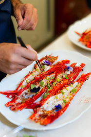 Fine dining seafood platter with lobster tails, edible flowers, and gourmet garnishes.