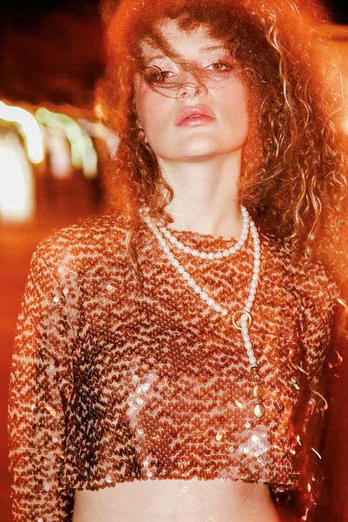 Urban night portrait in bronze sequin crop top and high-waist trousers