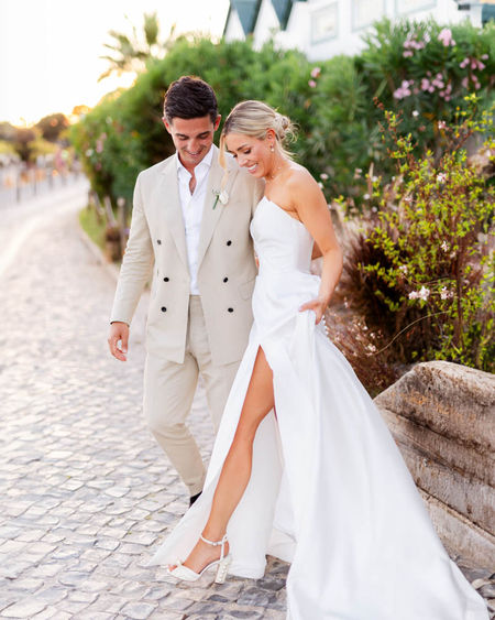 Bride and groom walking through a traditional whitewashed village street, documentary wedding photography Algarve Portugal