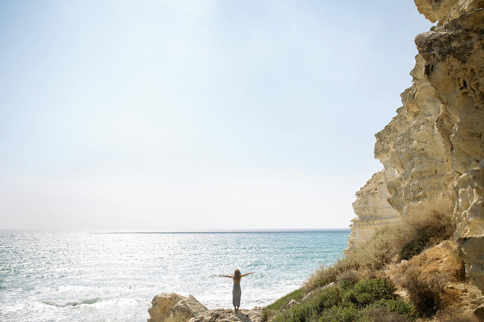 Woman Standing on Rock Formation Near Body of Water