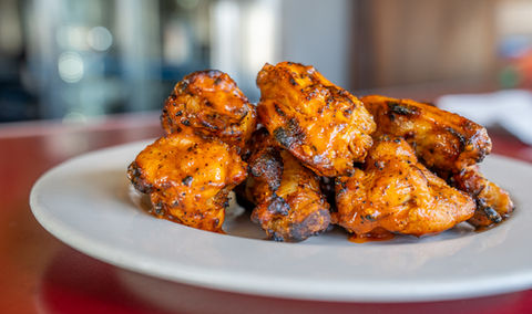 Close-up of delicious grilled chicken on white plate; food photography.