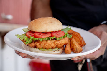 Fried chicken sandwich with tomato and lettuce on plate with potato wedges