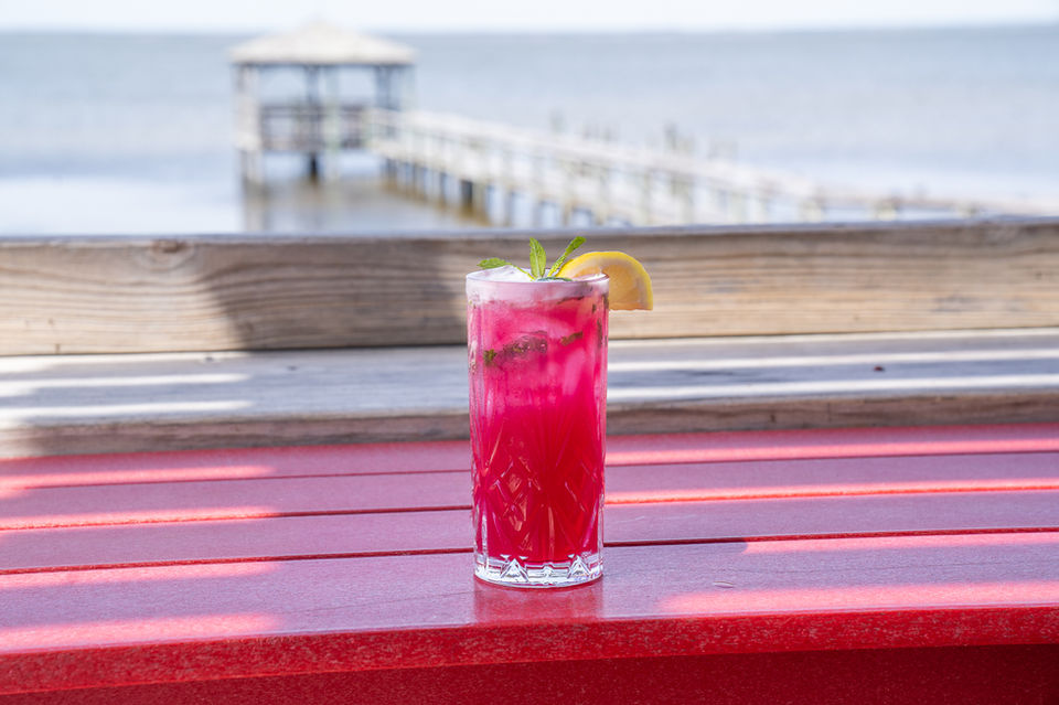 Bright red cocktail with mint and lemon slice at NC Coast Grill & Bar.