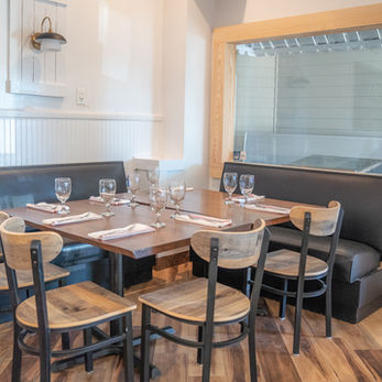 Restaurant dining table set with chairs and place settings near window.