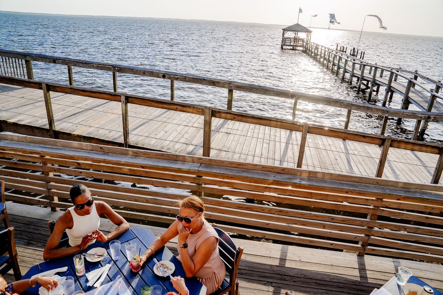 Two people dining at NC Coast Grill & Bar with ocean pier background