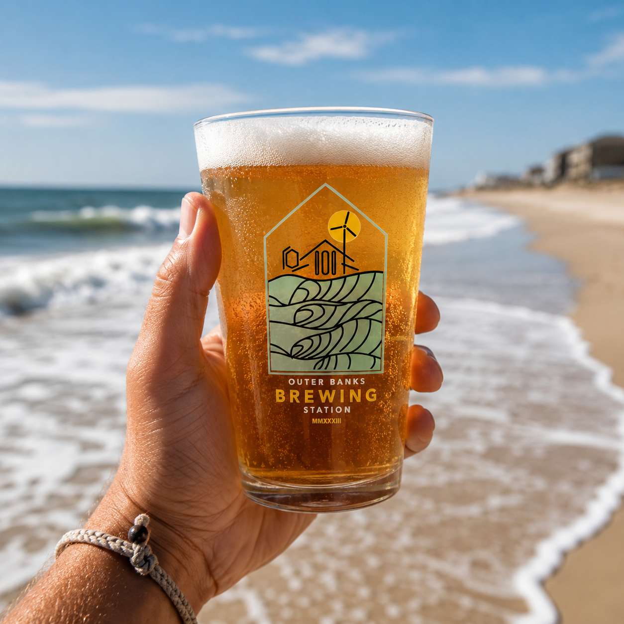Wave Set Pint Glass held at the beach with brewing logo.