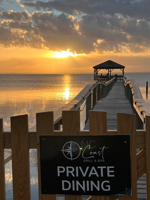 Sunset over the ocean pier with the NC Coast Grill & Bar background.