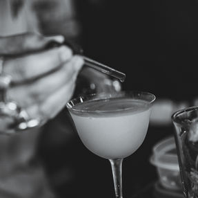 Bartender pouring cocktail into martini glass at The Kill Devil Grill bar.
