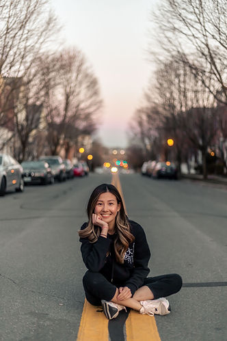 Huen, Washington DC portrait photographer, sitting on a yellow street line at dusk in a residential DC neighborhood