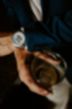 man holding a cocktail with a watch on