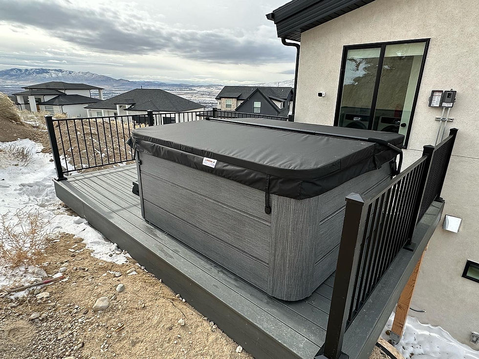 Covered hot tub on a deck with snow around. Mountain view, cloudy sky, and nearby houses. Mood is cold and serene.