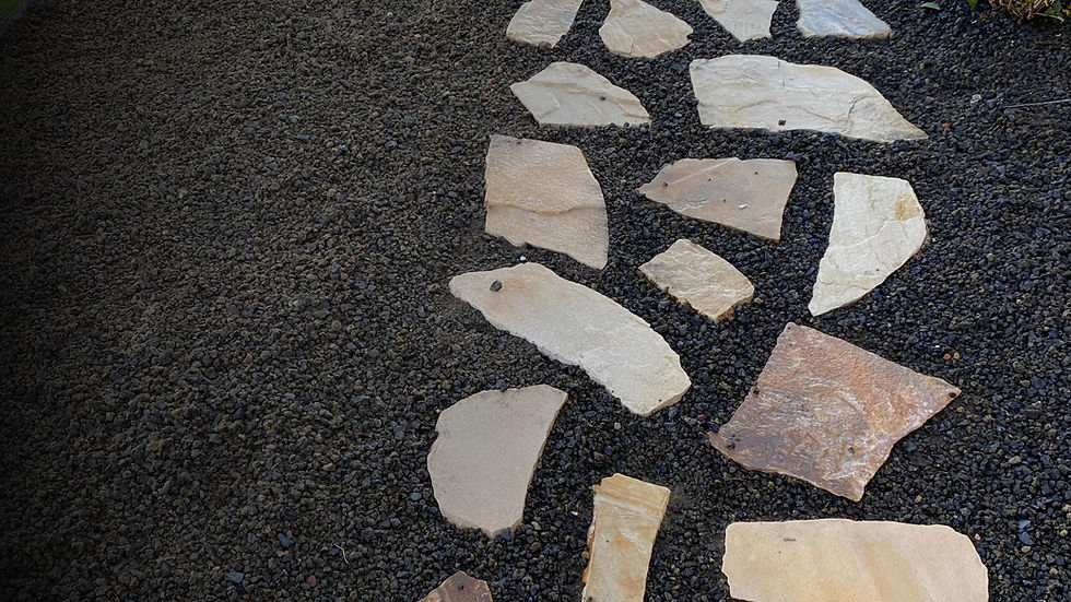Natural stone path set in dark gravel, creating a rustic outdoor walkway. Light tan stones contrast with the dark background.