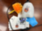 Pest control kit on a wooden table includes a white sprayer, orange duster, blue gloves, and labeled envelopes and brochure.