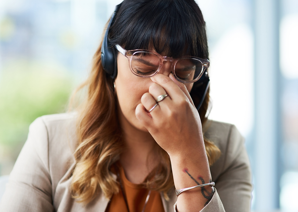 A woman lifting her glasses and pinching the inner corners of her eyes at the bridge of her nose, instinctively stimulating the Bladder 1 acupressure point to relieve eye strain and sinus pressure.