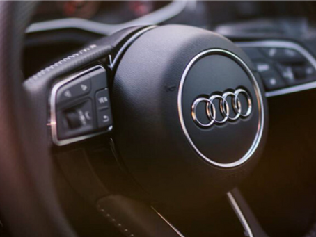 Audi steering wheel with logos on a blue background, featuring the text "BM Tech" in metallic letters below.