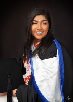 Graduation portrait of a woman in her robe with dark background by Angela Scott