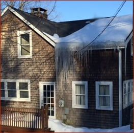House showing signs of roof ice dam formation after snowfall