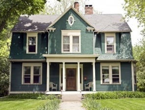 Green-shingled historic home with symmetrical windows and trim