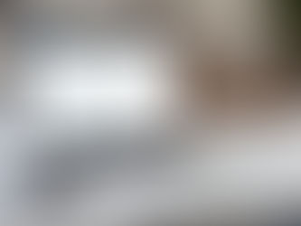 a laptop displaying financial charts and data sits on a white desk, accompanied by glasses, a notebook, and a calculator, suggesting a workspace setting for virtual bookkeeping.